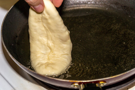 Woman frying pies in oil in a cast iron pan
