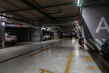 Underground Parking Garage A Corridor With Cars and Dim Lighting Under Industrial Ceiling.の写真素材