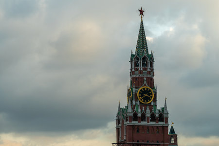 Spasskaya Tower Clock in Moscow Kremlin Under Cloudy Sky with Green Spires and Red Brick Facade