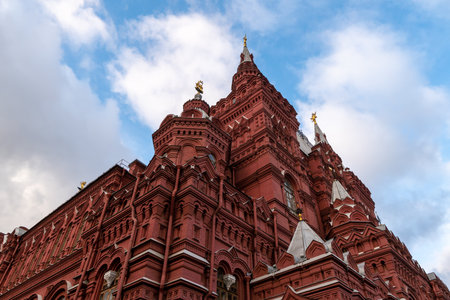 Grand Red Brick Cathedral-Style Building With Tall Towers and Spires Under Blue Sky.の写真素材