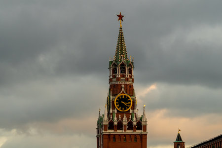 Spasskaya Tower Clock in Moscow Kremlin Under Cloudy Sky with Green Spires and Red Brick Facade.の写真素材