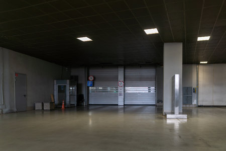 A spacious industrial interior featuring large roll-up metal doors, concrete floor, and sparse...