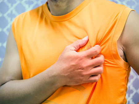 A picture of a man gripping his left chest in pain because of a heart attack. Concept of heart...