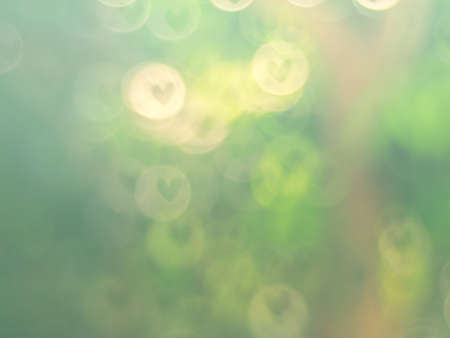 Heart-shaped blurred lens bokeh background representing love.の写真素材