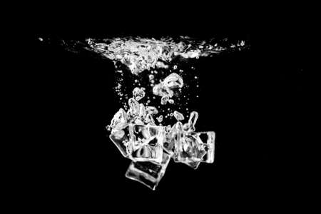 Water splash abstract shape with ice cubes isolated on black background.の写真素材