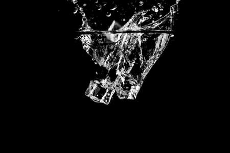 Water splash abstract shape with ice cubes isolated on black background.の写真素材