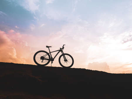 The silhouette of a mountain bike parked high in the mountains in the evening is beautiful with a...