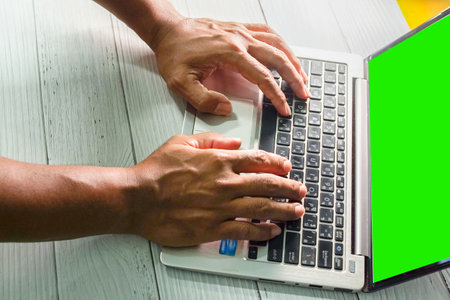 Close up of man hands typing on laptop keyboard with green screen.
