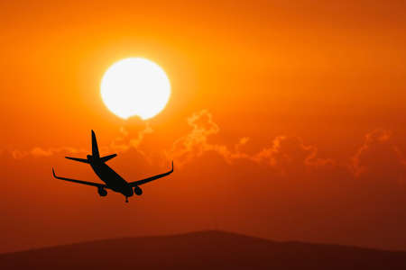 Silhouette of a passenger flight story with tourists landing at the airport. Airplane landing at...