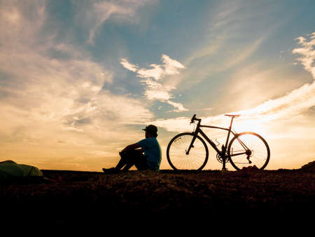 Silhouette of cyclists with bicycles at sunset. silhouette of a person with a bike at sunset. beautiful landscape image with Bicycle at sunsetの写真素材