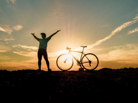 Silhouette of cyclists with bicycles at sunset. silhouette of a person with a bike at sunset. beautiful landscape image with Bicycle at sunsetの写真素材