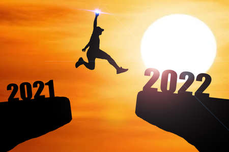 Concept Happy new year 2022 Silhouette image of happy man from 2021 up to 2022 on beautiful skyの写真素材
