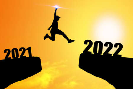Concept Happy new year 2022 Silhouette image of happy man from 2021 up to 2022 on beautiful skyの写真素材