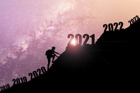 Man climbing mountains and going through and changing 2019 ,2020 to enter 2021. Happy New Year 2021 concept. Happy new year and holiday concept. Vintage tone filter effect color style. Success new year concept.の写真素材