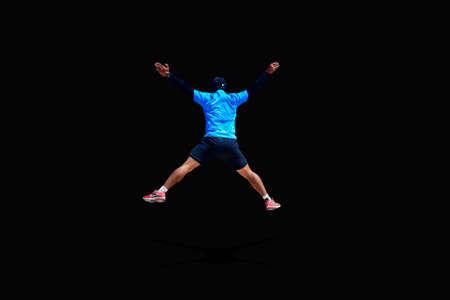Man jumping with arms and legs spreading joyfully on colored backgroundの写真素材