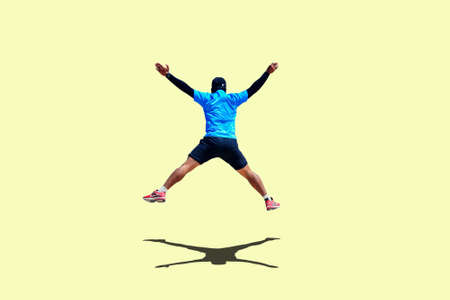 Man jumping with arms and legs spreading joyfully on colored backgroundの写真素材