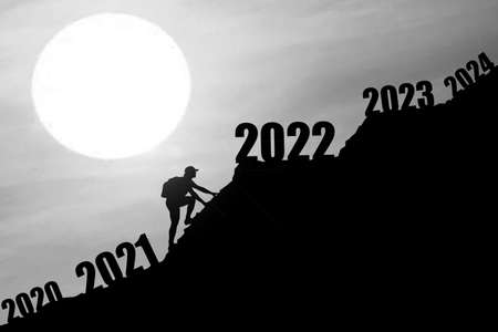 Man climbing mountains and going through and changing 2020 ,2021 to enter 2022. Happy New Year 2022 concept. Happy new year and holiday concept.Success new year concept.の写真素材