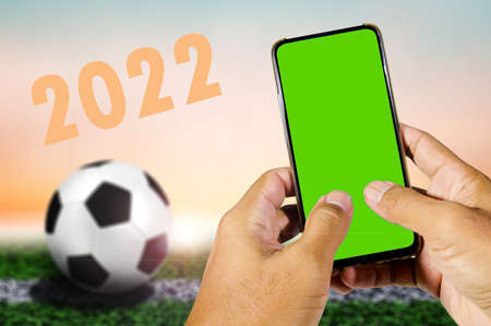 green blank screen mobile phone in man's hand with football background
