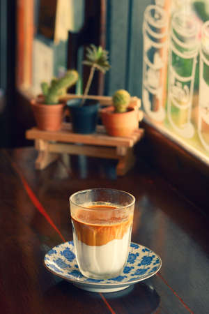 A cup of strong coffee with milk is placed on the table in the morning.