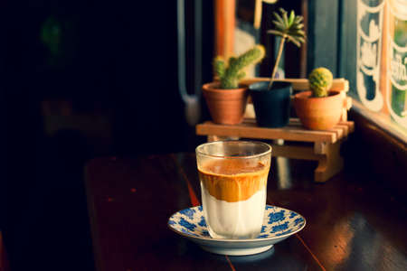 A cup of strong coffee with milk is placed on the table in the morning.