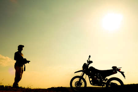 Silhouettes of professional landscape travel photographers. with a motocross in the eveningの写真素材