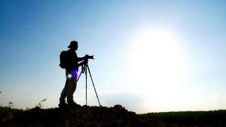 gesture silhouette Professional landscape travel photographer taking pictures on the mountain.の写真素材