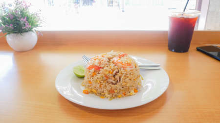 The delicious shrimp fried rice in a white plate is placed on a wooden table.の写真素材