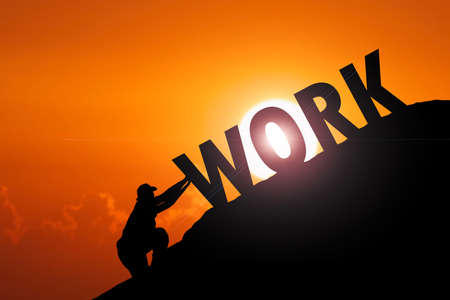 Man pushing the word Work to the top of the mountain. The concept of hard work. hard work businessの写真素材