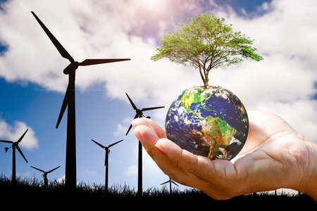 Clean energy concept to reduce global warming. hand holding a globe with a tree The background is a...