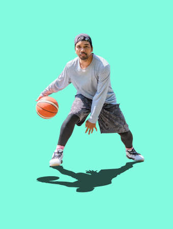 Full body photo of Asian man playing basketball in leisure clothes on a colored background with...