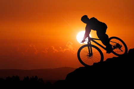 Silhouette of a cyclist riding a mountain bike at sunset. Extreme sport.の写真素材
