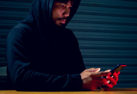 Mysterious man in hoodie on dark background. Dangerous criminal. Silhouette of man in the hood, dark...