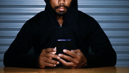 Mysterious man in hoodie on dark background. Dangerous criminal. Silhouette of man in the hood, dark mysterious man hoodie, murderer, hacker, anonymus on the black background with free spaceの写真素材