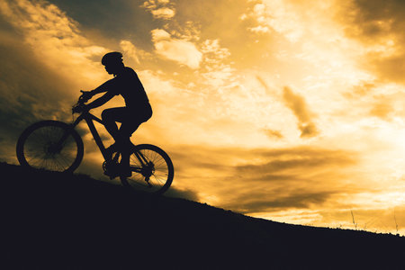 Silhouettes of touring cyclists practicing in the mountains offer beautiful views in the evening.Adventure tourists by bicycle. adventure conceptの写真素材