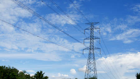 High voltage power poles in rural Thailand. High-voltage power lines passing through a plowed field, on the background of a beautiful cloudy sky.の写真素材