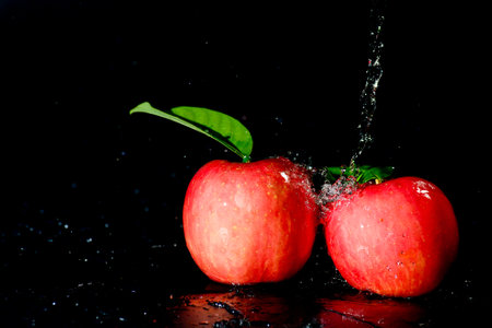 Red apples in water splash over black background. Apple water splash on black background