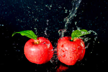 Red apples in water splash over black background. Apple water splash on black backgroundの写真素材