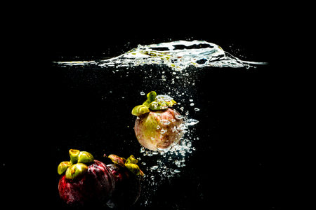 Mangosteen in splashing water on a black background refreshingの写真素材