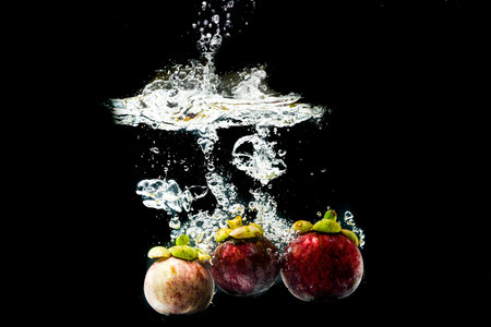 Mangosteen in splashing water on a black background refreshingの写真素材