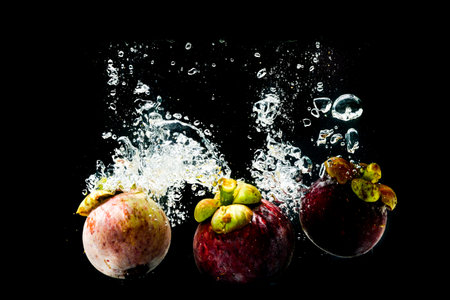 Mangosteen in splashing water on a black background refreshingの写真素材