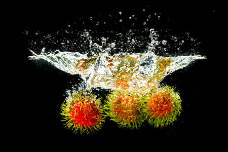 Rambutan, Thai fruit in splashing water on a black background. refreshing