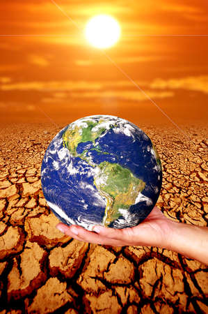 Hand holding a globe on dry land. concept of global warming and environment and changeの写真素材
