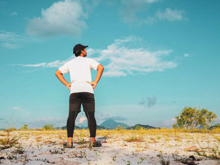 An Asian man is taking a walk in the sand on a nice day. Exercise and relaxation conceptsの写真素材