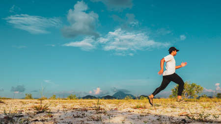 An Asian man practicing running in the sand on a nice day. Training and Exercise Conceptsの写真素材