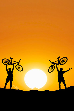 Silhouettes of touring cyclists practicing in the mountains offer beautiful views in the evening.Adventure tourists by bicycle. adventure concept. Silhouettes of 3 men happily raising bicycles in the evening.の写真素材