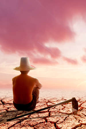 A man in a white hat with an ax on a cracked earth backgroundの写真素材