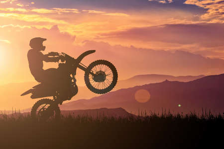 Silhouette of a motocross motorcycle lifting the front wheel. Adventure and Action Conceptsの写真素材