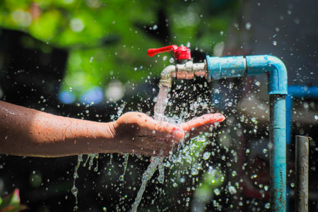 Water concept in everyday life. Hands supporting the water flowing from the faucet. water splashing from the tapの写真素材
