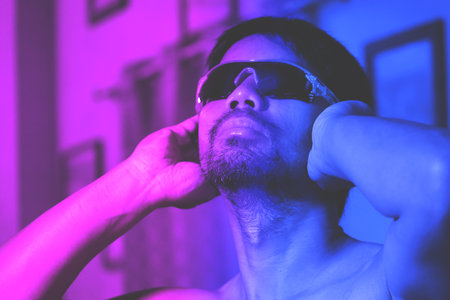 Lonely Asian man on blue and pink studio background in mixed neon light. Cool handsome model. concept of human emotions facial expressions sales advertisement fashion copy spaceの写真素材