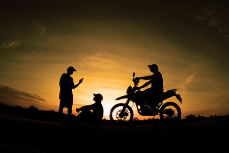 Silhouette of a motorcyclist and his daughter at sunsetの写真素材